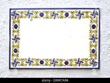 collage, insegne di ceramica in smalto o argilla su una parete rustica luminosa. i fiori blu, gialli, le foglie verdi sono disegnate con motivi gialli. lastra di pietra quadrata Foto Stock