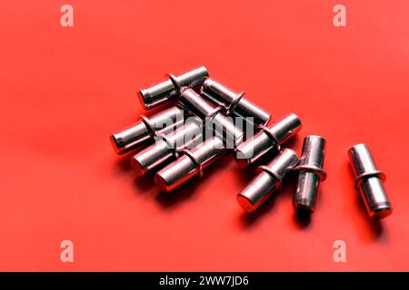 Accessori per armadi. Un gruppo di supporti per ripiani metallici su sfondo rosso. Primo piano. Foto Stock