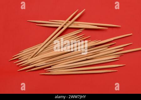 Gli stuzzicadenti in bambù si trovano in una pila su sfondo rosso. Foto Stock