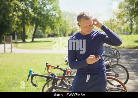 Uomo maturo in posizione di stazionamento per ascoltare musica sullo smartphone Foto Stock