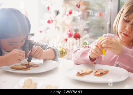 Due giovani ragazze decorare lo zenzero pane biscotti di uomo Foto Stock