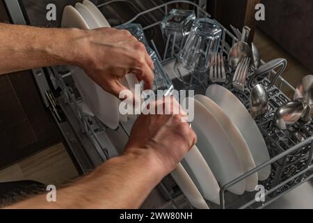 Caricamento dei piatti sporchi in lavastoviglie, lavastoviglie in tavoletta, aiuto in cucina, risparmio d'acqua Foto Stock