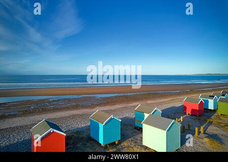 Findhorn Moray Coast Scozia cielo azzurro luminoso su colorate capanne sulla spiaggia che guardano alla spiaggia di sabbia fino al mare Foto Stock