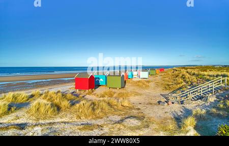 Findhorn, Moray Coast Scotland, colorate capanne sulla spiaggia di sabbia e sul mare blu Foto Stock