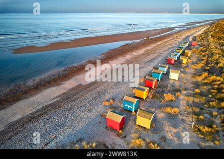 Findhorn Moray Coast Scozia in tarda serata e una fila di colorate capanne sulla spiaggia che si affacciano sull'estesa costa Foto Stock