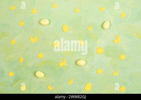 Easter card monocromatica. Disposizione di decorazioni pasquali gialle uova, fiori, farfalle su sfondo verde giallo. Vista dall'alto. Posizione piatta. Foto Stock
