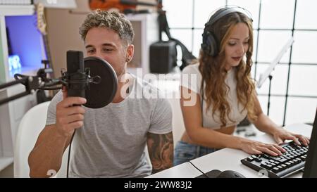 Un uomo e una donna registrano musica insieme in uno studio moderno con attrezzature professionali. Foto Stock