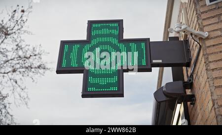 Segnaletica verde illuminata della farmacia con luci a LED su un muro di mattoni e cielo limpido a murcia, spagna. Foto Stock