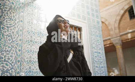 Una giovane donna sorridente ammira le piastrelle ornate dello storico palazzo topkapi di istanbul mentre viaggia in turchia. Foto Stock