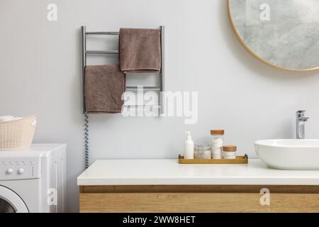 Portasciugamani riscaldato con asciugamani marroni in bagno Foto Stock
