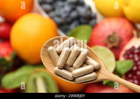 Pillole vitaminiche in cucchiaio sulla frutta fresca, vista dall'alto Foto Stock