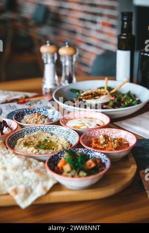 Un assortimento di mezze mediterranee servite con verdure fresche, hummus e pane pita su una tavola di legno. Foto Stock