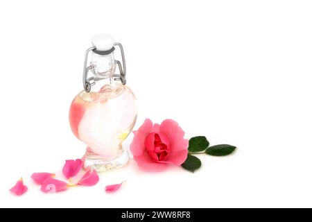 Rosewater con fiore rosa e bottiglia a forma di cuore. Pelle sana e naturale per idratare la pelle, ridurre il rossore, l'irritazione, trattare cicatrici, ustioni. Foto Stock