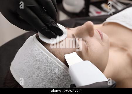 Cosmetologo che utilizza lo scrubber a ultrasuoni, primo piano. Cliente con procedura di pulizia in ambienti chiusi Foto Stock