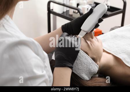 Cosmetologo che utilizza lo scrubber a ultrasuoni, primo piano. Cliente con procedura di pulizia in clinica Foto Stock