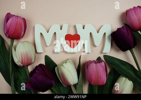 Tema della festa della mamma con lettere e decorazioni floreali su sfondo rosa Foto Stock