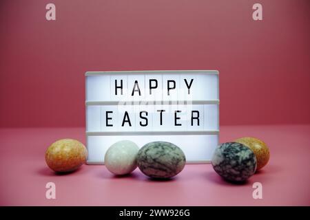 Scatola luminosa di buona Pasqua con decorazione degli elementi pasquali su sfondo rosa Foto Stock