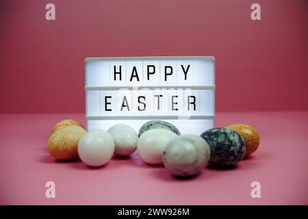 Scatola luminosa di buona Pasqua con decorazione degli elementi pasquali su sfondo rosa Foto Stock