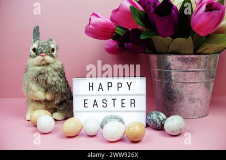 Scatola luminosa di buona Pasqua con decorazione degli elementi pasquali su sfondo rosa Foto Stock