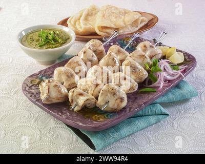 Pollo Malai Boti o Chicken Cream Marinated Kabab è un piatto unico e delizioso barbecue. Serve con salsa al peperoncino verde e paratha caldo. Foto Stock