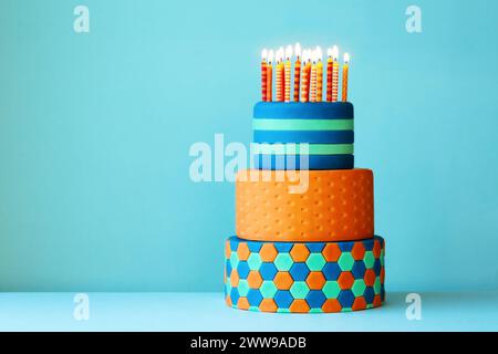 Torta di compleanno dai colori vivaci ricoperta di fondente, tre strati e colorate candele di compleanno Foto Stock