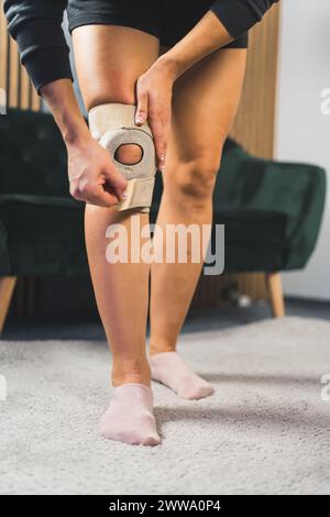 primo piano verticale di una donna che applica un sostegno protettivo al ginocchio, concetto di assistenza sanitaria. Foto di alta qualità Foto Stock