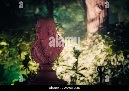 Un busto di Voltaire illuminato in un giardino che trasuda contemplazione storica e filosofica. Foto Stock