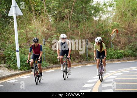 tre giovani ciclisti asiatici in bicicletta all'aperto su strade rurali Foto Stock