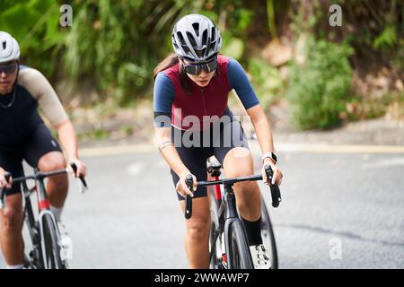 giovani atleti di ciclismo asiatici che cavalcano in bicicletta all'aperto su strade rurali Foto Stock