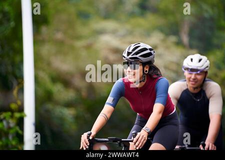 giovani coppie asiatiche ciclisti in bicicletta su strada rurale Foto Stock
