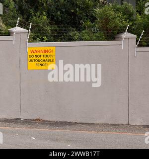 Recinzione elettrica, avvertenze e cartelli sulla parete dell'hotel per avvertenze, notifiche e informazioni. Segnaletica pubblica, simbolo e edificio con bordo Foto Stock