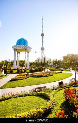 La torre della televisione di Tashkent Toshkent Teleminorasi e la colonna commemorativa con tetto rotondo nel parco al tramonto in Uzbekistan Foto Stock