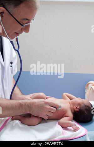 Il pediatra controlla la frequenza cardiaca del neonato. Foto Stock