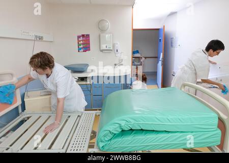 Assistenti di assistenza all'infanzia che puliscono una stanza dopo che un paziente lascia la suite di pannolini. Foto Stock