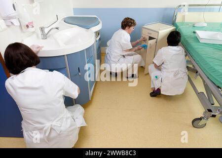 Assistenti di assistenza all'infanzia che puliscono una stanza dopo che un paziente lascia la suite di pannolini. Foto Stock