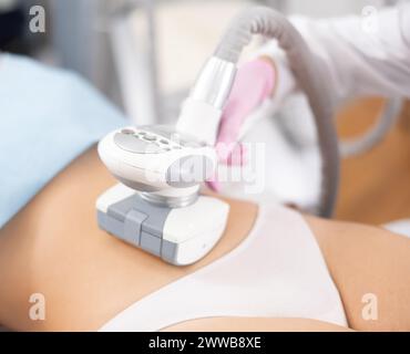 Massaggiatore irriconoscibile che esegue un massaggio anticellulite per il ventre di una giovane donna in clinica di medicina estetica Foto Stock