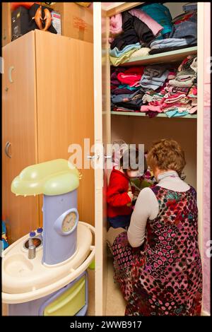 ASE - assistenza sociale infantile. Isabelle sceglie i vestiti con Sarah da un guardaroba nella sua camera da letto. SOLO PER USO EDITORIALE. Foto Stock