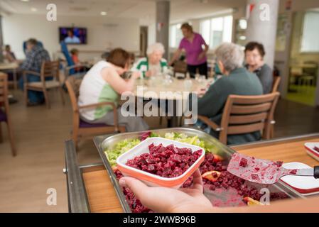 EHPAD - distribuzione dei pasti agli anziani residenti nel refettorio della sala comune. Foto Stock