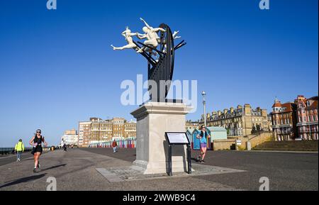 Brighton Regno Unito 23 marzo 2024 - i corridori passano accanto alla scultura Flight of the Langoustine su Hove Plinth sul lungomare in una mattinata soleggiata ma fredda lungo la costa meridionale. La scultura è stata creata dallo scultore di Brighton Pierre Diamantopoulo ed è la seconda ad abbellire Hove Plinth : accreditamento Simon Dack / Alamy Live News Foto Stock
