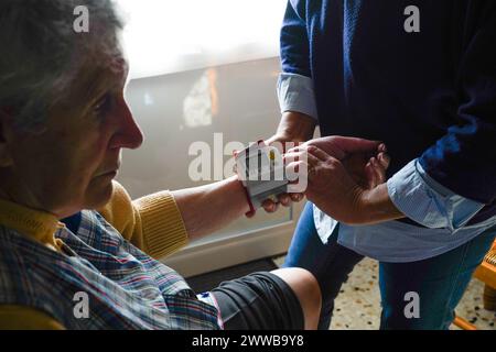 Infermiera freelance durante la sua visita quotidiana ad una persona anziana. Pressione sanguigna in corso. Foto Stock