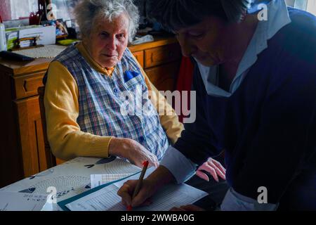 Infermiera freelance durante la sua visita quotidiana ad una persona anziana. Follow-up medici. Foto Stock