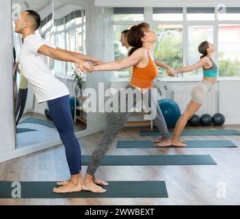 Gli amanti dello stile di vita attivo si esibiscono in una posa di equilibrio con il backbend yoga in palestra Foto Stock