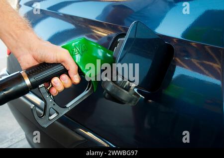 La mano di un uomo tiene la pistola a gas, fa rifornimento in una stazione di servizio. Vista ravvicinata. Foto Stock