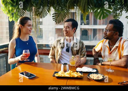 Giovani allegri che si incontrano al bar sul tetto per passare un po' di tempo Foto Stock