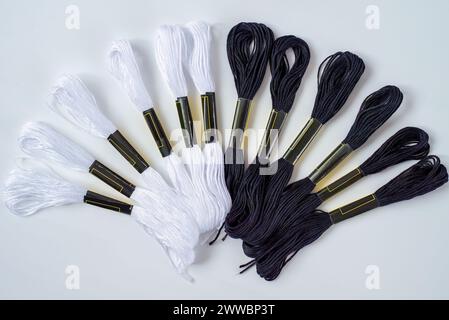 Molti spille in bianco e nero di filo a bocce per ricami su una fila in cerchio su sfondo bianco Foto Stock