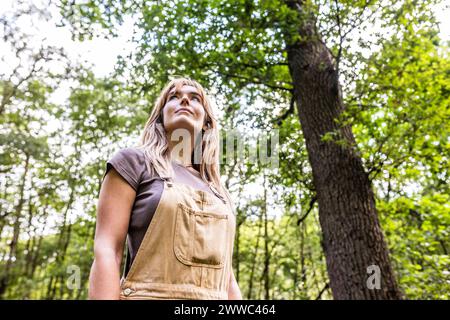 Donna in piedi nella foresta vicino agli alberi Foto Stock