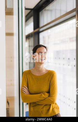 Giovane donna d'affari felice in piedi con le braccia incrociate Foto Stock