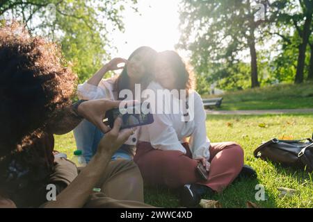 Giovane che scatta foto agli amici tramite smartphone al parco Foto Stock