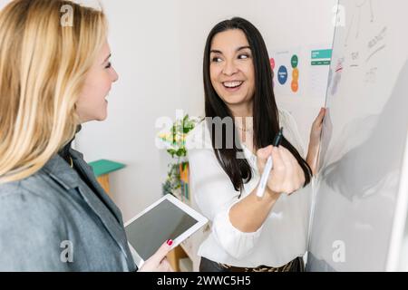 Giovane donna d'affari felice che discute con un collega che possiede un tablet PC Foto Stock