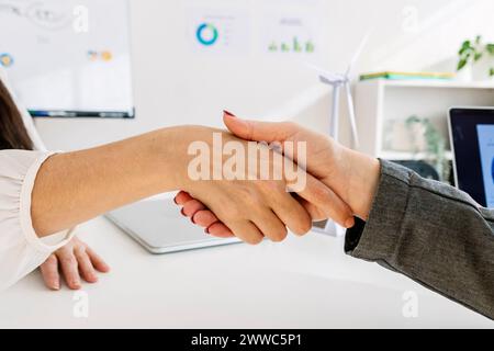 Donne d'affari che stringono la mano alla scrivania Foto Stock